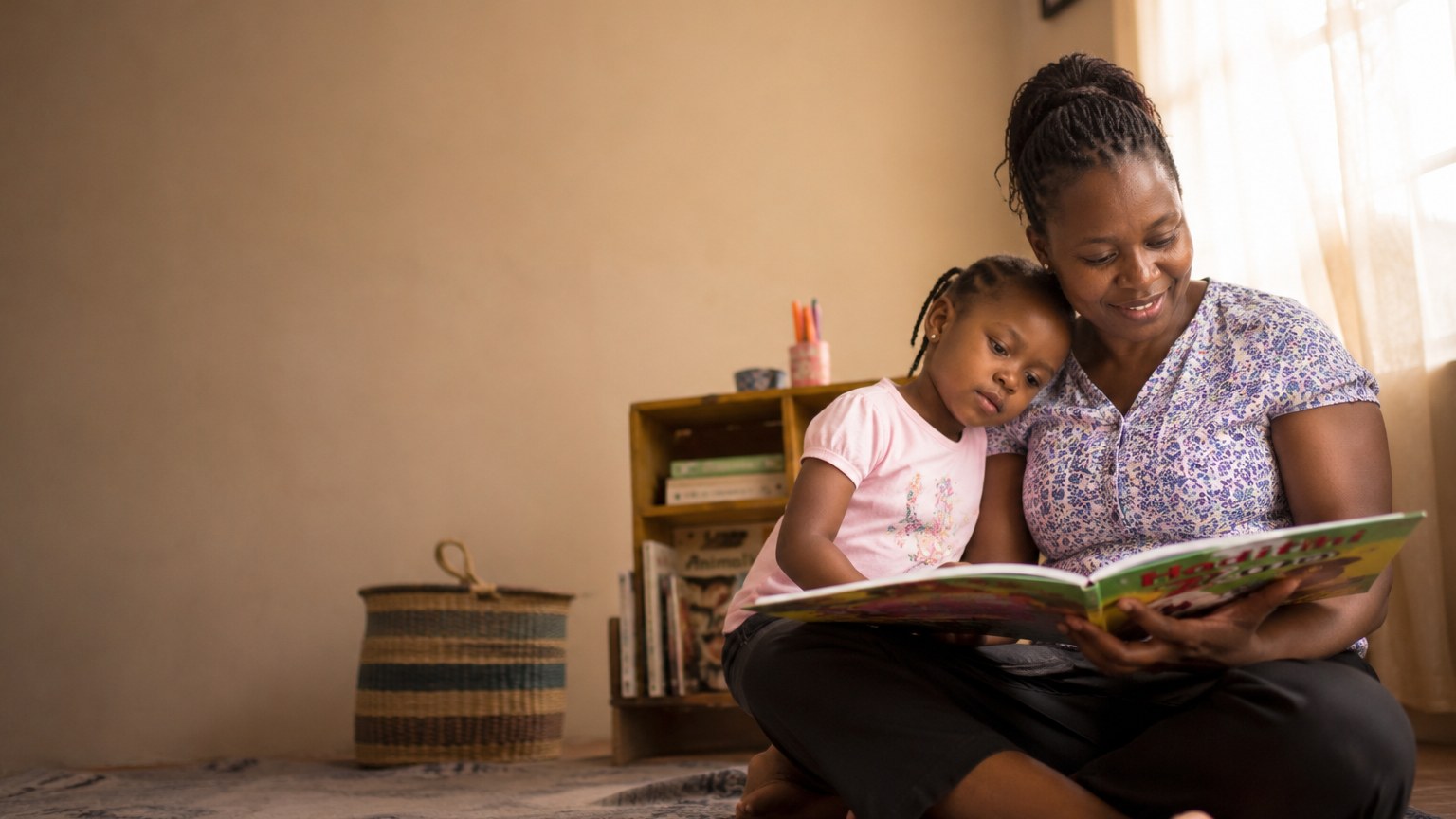 A nanny reading with a child in a bright living room